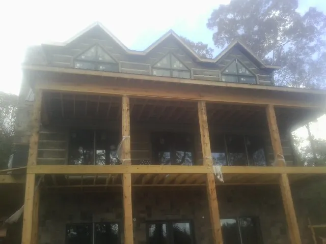 Dormers and porch framing on a large log home under construction — Roof Coating work by our crew in Delavan