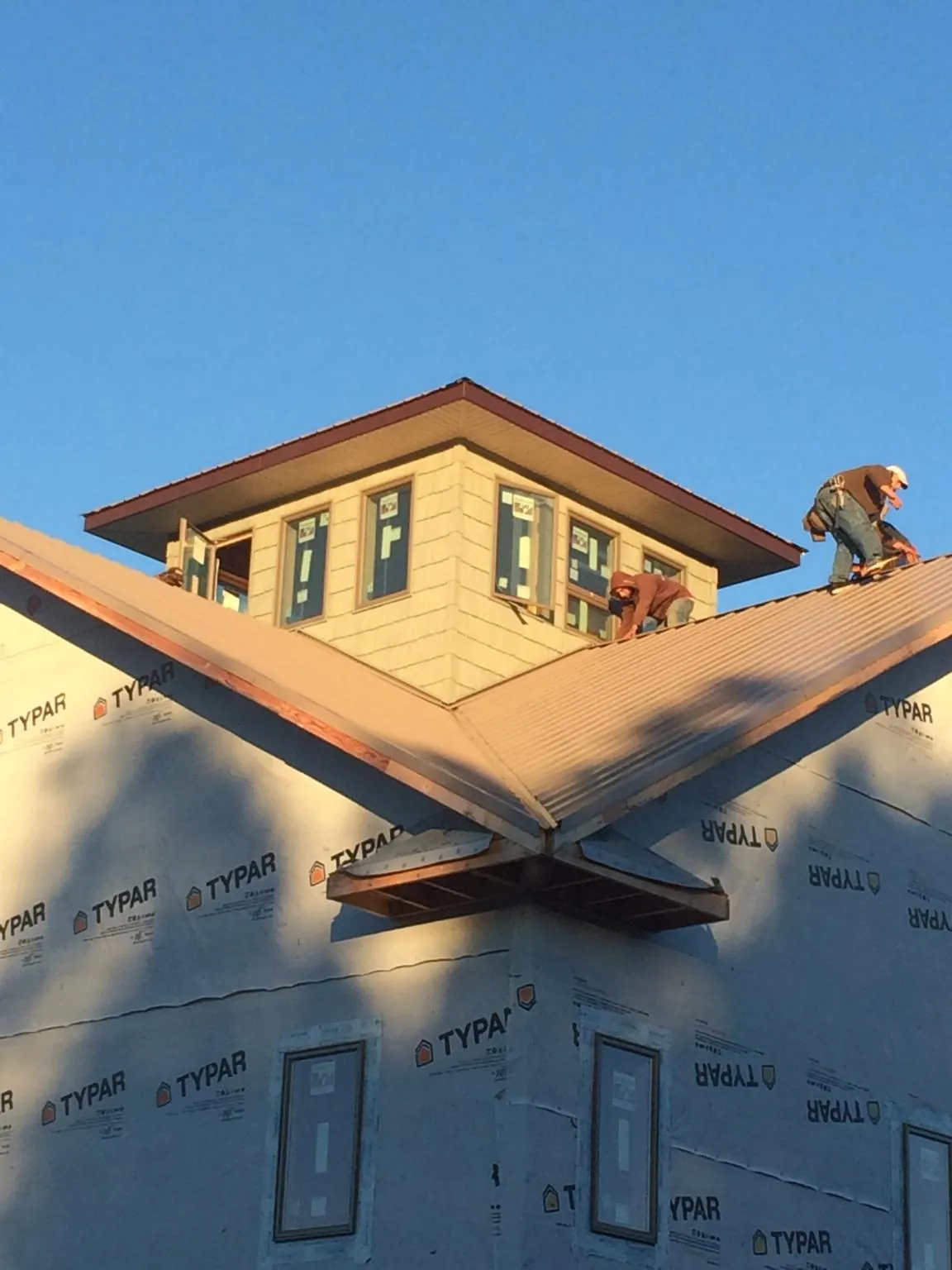 Roofers working around a rooftop cupola on a new metal roof at sunset — Roof Waterproofing in Delavan by Roofing Brothers